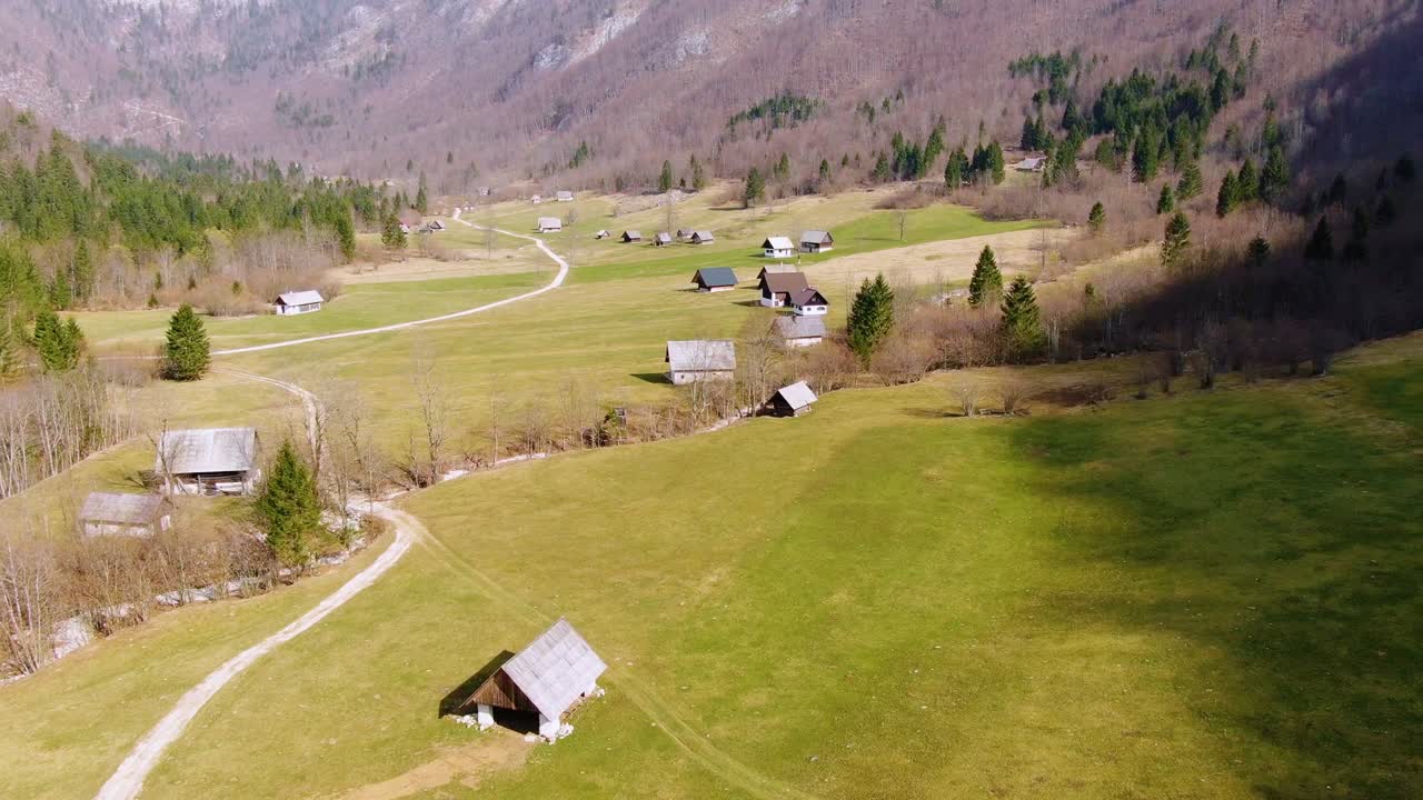 Aerial Over Trees To Reveal Valley Floor With Houses On Green Grass Landscape