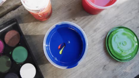 overhead view of paints on table in sunny garden, slow motion