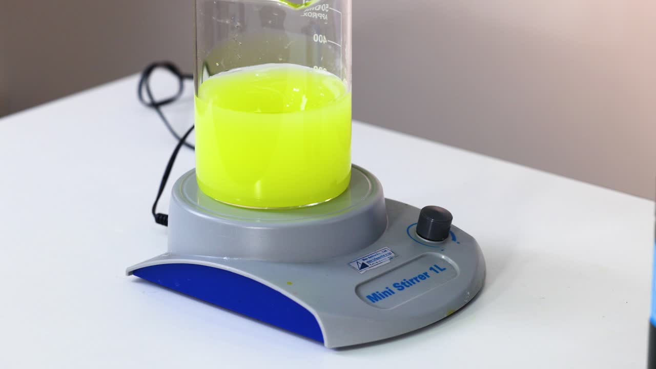 Yellow liquid being stirred in a flask with a mini stirrer