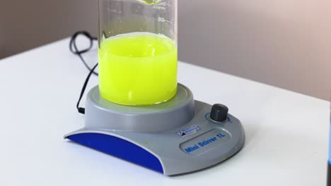 yellow liquid being stirred in a flask with a mini stirrer