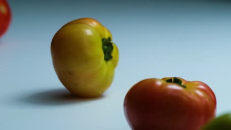Los-Tomates-Rojos,-Verdes-Y-Amarillos-Caen-Y-Ruedan-Sobre-La-Mesa,-Al-Revés