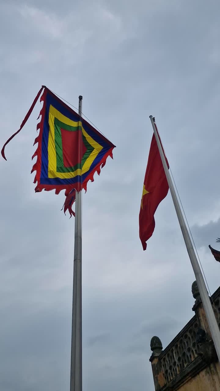 Vertikale Ansicht: Vietnamesische Nationalflagge und traditionelle Fünf-Farben-Flagge wehen an Masten