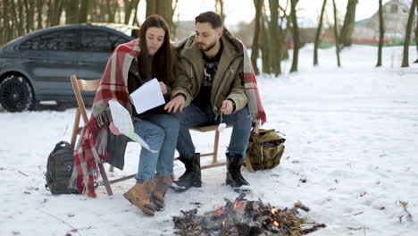 caucasian couple camping in a snowed forest.