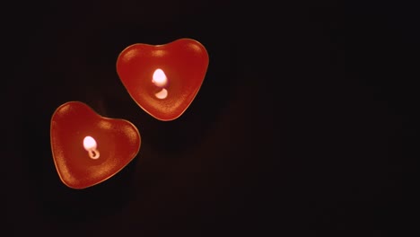 Close-Up-Of-Two-Romantic-Lit-Heart-Shaped-Red-Candles-On-Black-Background-With-Copy-Space-1