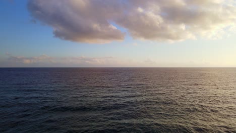 sunset reflecting on calm waters out at sea as drone flys over