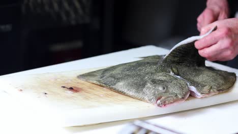 Fish-vendor-cutting-a-turbot-for-the-clients,-with-black-background