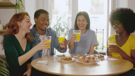 diverse friends toasting with orange juice at brunch