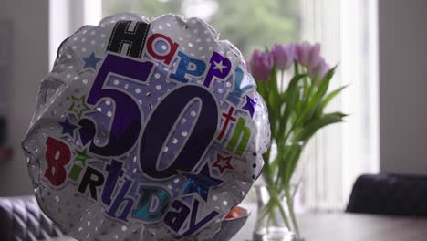 Balloon-for-fiftieth-birthday-with-flowers-and-window-in-background