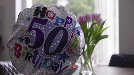 globo para el quincuagésimo cumpleaños con flores y ventana en segundo plano.