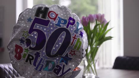 balloon for fiftieth birthday with flowers and window in background