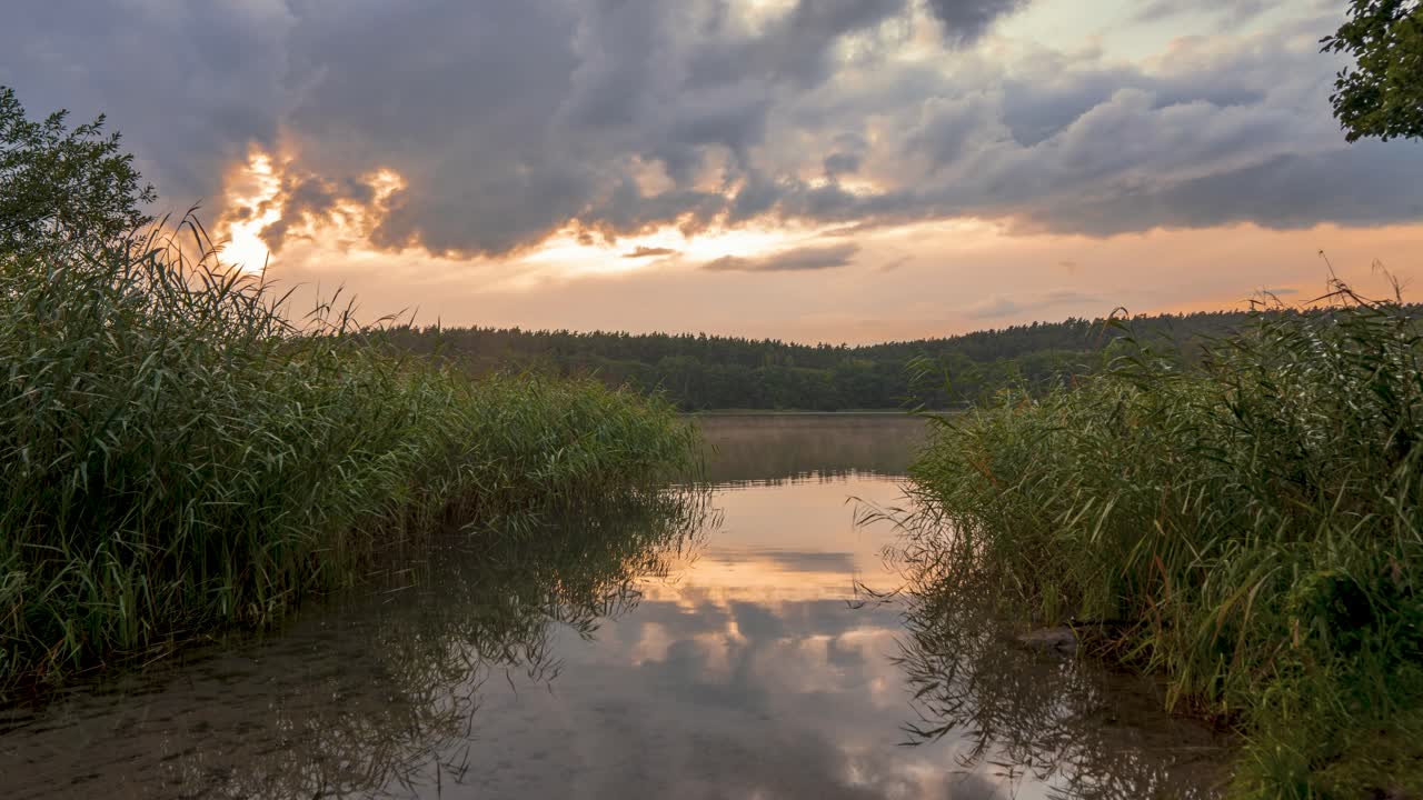 lapso de tiempo en un pequeño lago forestal con el sol poniéndose y las nubes pasando