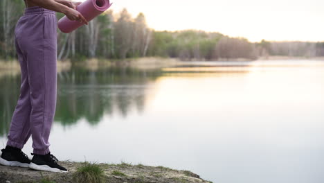 woman unrolling a mat in the forest