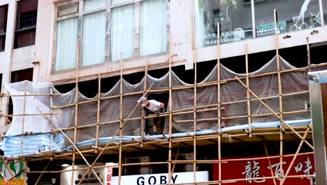 worker repairing scaffolding on a building facade