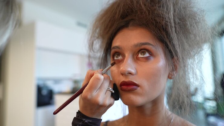 Junge Frau bekommt Lidschatten von Make-up-Artistin aufgetragen