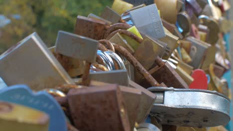 Close-up-lots-of-padlocks-connected-to-railings-on-bridge-over-water-close-up