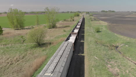 día de toma aérea de drones sobre la cabeza de los vagones de tren abiertos que se mueven en la vía por campo