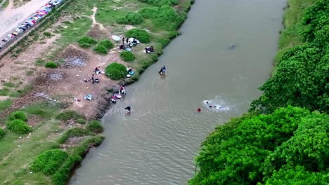 vista aérea de niños haitianos nadando en un río sucio y adultos lavando ropa - país pobre de haití