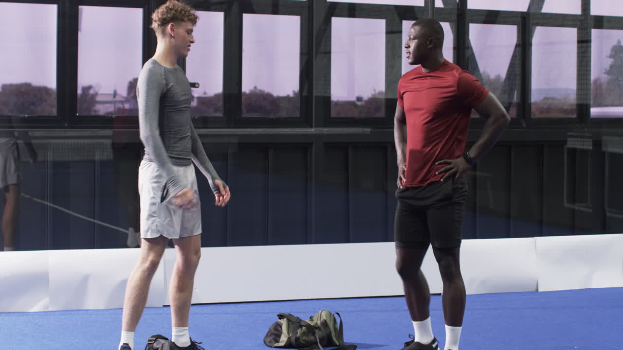 Two diverse men practicing padel tennis footwork on indoor court, focusing on technique