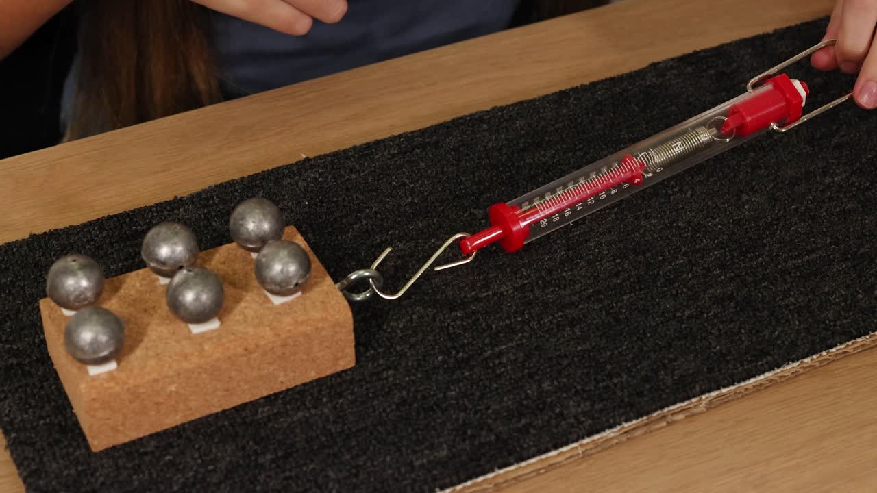 A hands-on physics experiment using a spring scale to measure friction and force on a weighted block over carpet