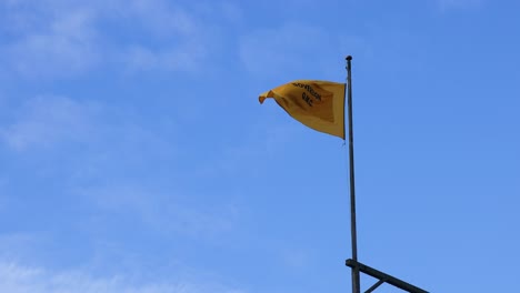 yellow flag waving against a blue sky