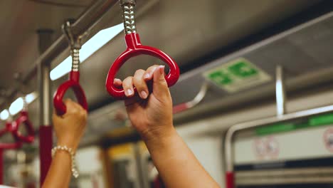 hands gripping handles in hong kong subway