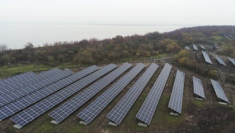 Solar-panel-array-rows-aerial-view-misty-autumn-woodland-countryside-orbit-right-low