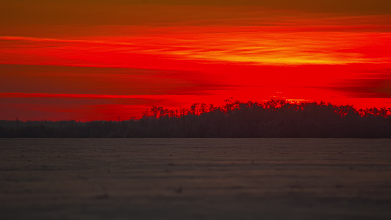 Close up timelapse of red colored sun sinking behind horizon during snowy winter day
