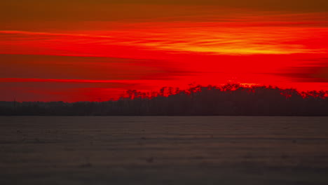 close up timelapse of red colored sun sinking behind horizon during snowy winter day