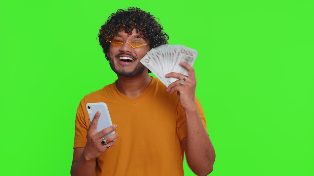 Indian man use smartphone rejoicing win receiving money dollar cash success lottery jackpot luck