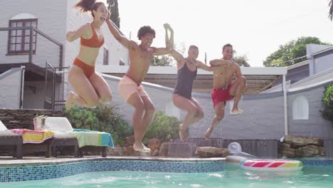 Group-of-happy-diverse-female-and-male-friends-holding-hands,-jumping-into-pool-at-pool-party