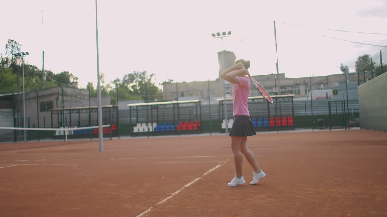 천천히 공을 돌려주는 코트에서 테니스를 하는 젊은 백인 여성