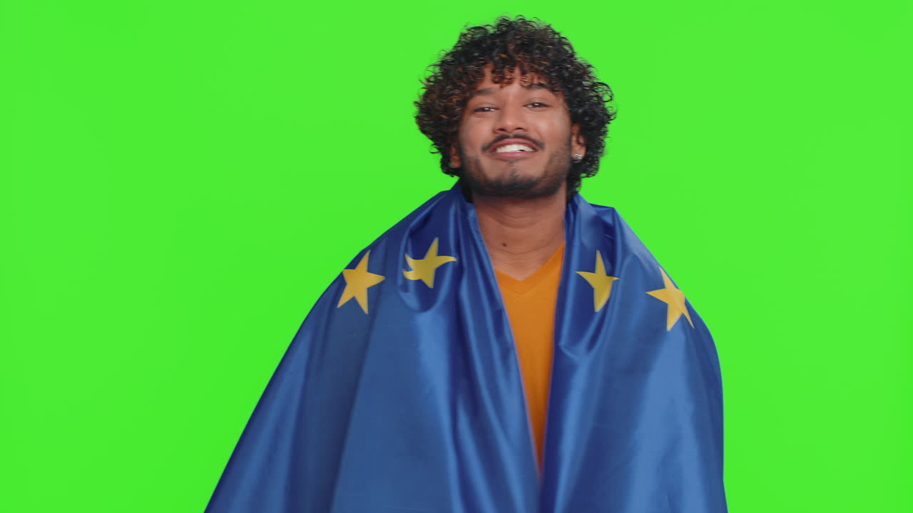 Happy young indian man waving european union flag smiling cheering democratic laws human rights