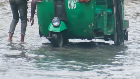 man pulling rickshaw through floodwater