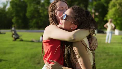 two happy young girls with dreads hugging each other. excited female friends embracing each other and laughing during the sunny