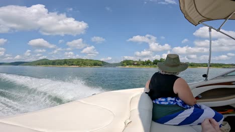 woman in rear of cockpit of sports boat that is cruising on table rock lake on a cloudy afternoon