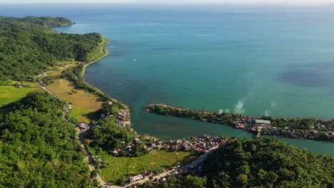 Stunning aerial view of a coastal village community with turquoise ocean waters and lush hills at Batalay, Catanduanes, Philippines.