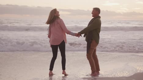 active senior couple holding hands on beach