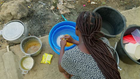 View-from-the-top-of-a-woman-washing-dishes-in-front-of-her-house-in-a-village-in-Kumasi,-Ghana-in-Africa