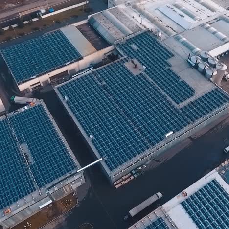 innovative solar farm on roofs. blue solar panels on the top of industrial buildings of a plant. renewable source of energy. future technology concept. aerial view.