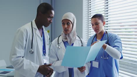 front view of multi-ethnic doctors discussing over medical report in hospital