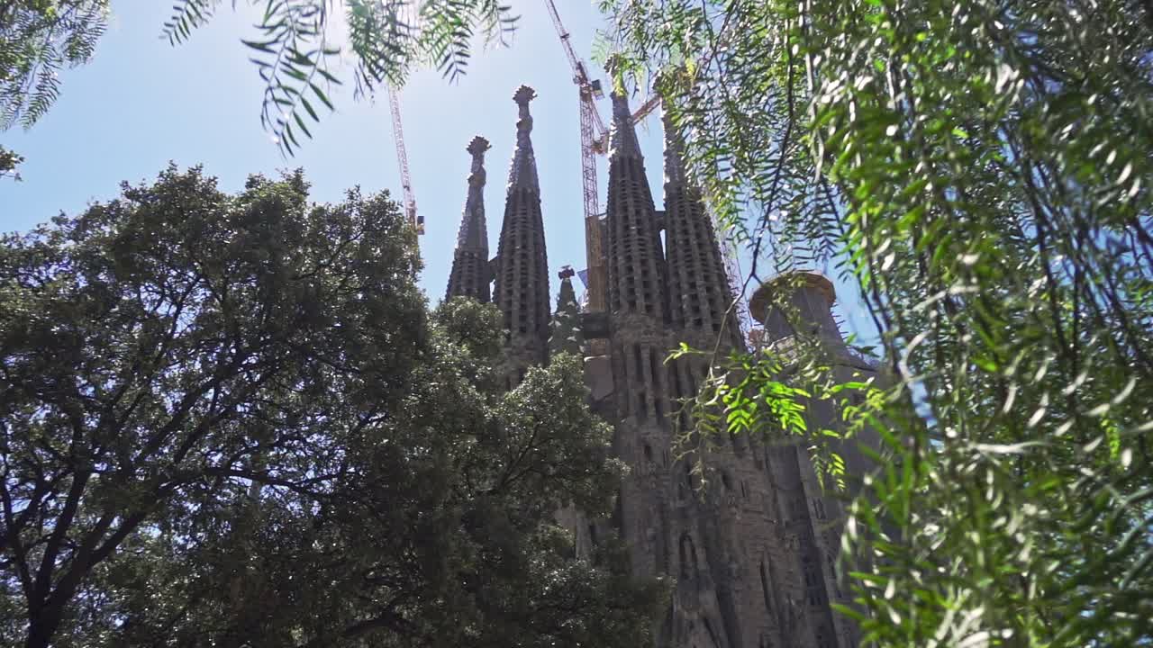 Old catholic church in tree leaves. Historical building by Antonio Gaudi