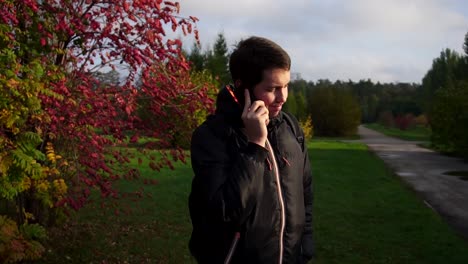 hombre hablando por teléfono en el parque de otoño