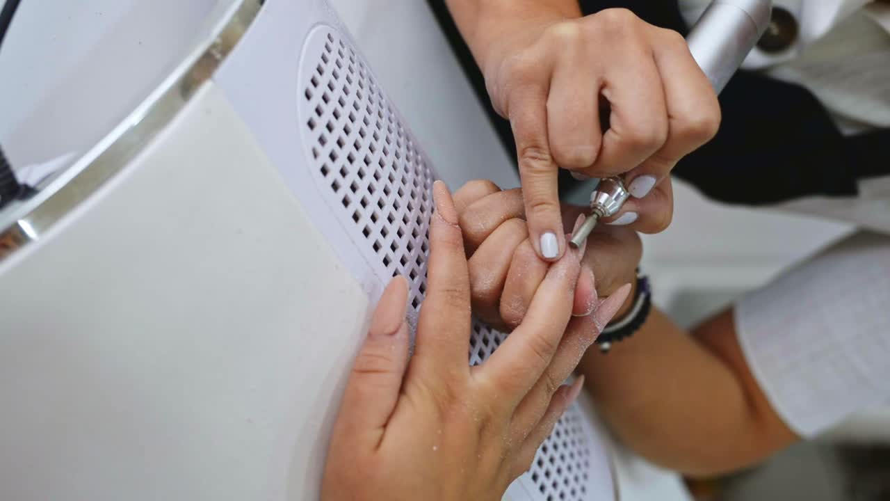 artista de uñas de cosecha quitando el esmalte de uñas del cliente en el salón
