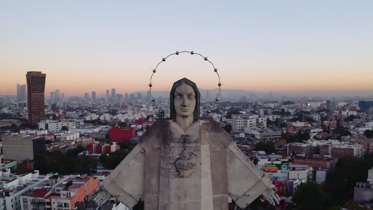 Medium wide backwards flying aerial drone shots of massive Jesus status towering over Mexico City at sunset, featuring Parroquia del Purism Corazon de Maria and buildings in the back