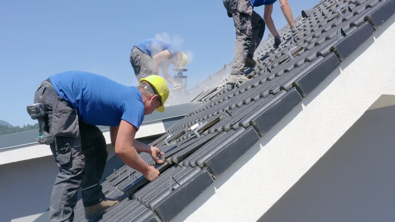 Filmato statico di operai che forano e preparano le piastrelle sul tetto di una casa per l'installazione di pannelli solari. Concetto di professionalità, lavoro, energia solare, energia rinnovabile. Vista laterale