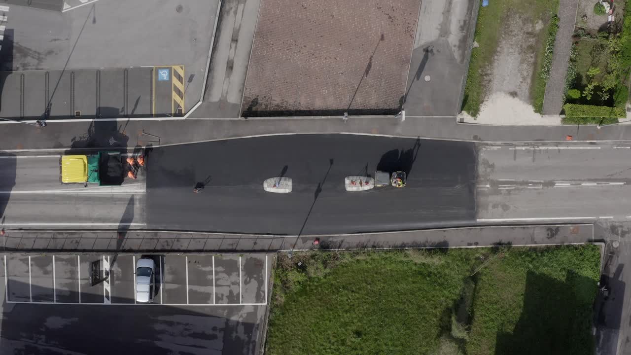 Top down aerial shot above the road paving with road workers and machines.