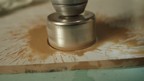 worker drills a round hole in ceramic tile with diamond crown, closeup