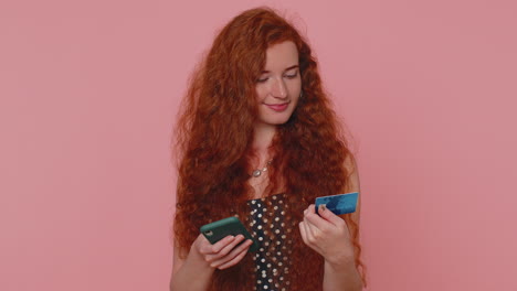 redhead girl use credit bank card and smartphone while transferring money purchases online shopping