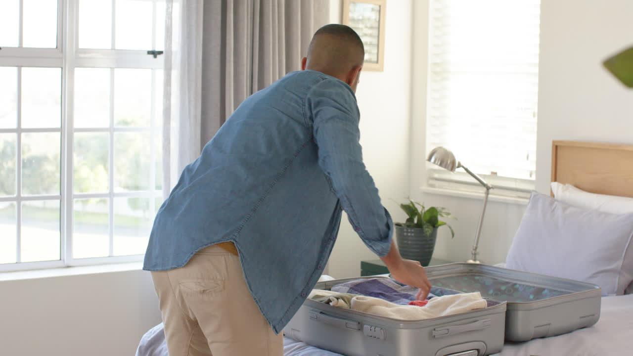 밝은 침실에서 가방을 는 행복한 두 인종의 남자