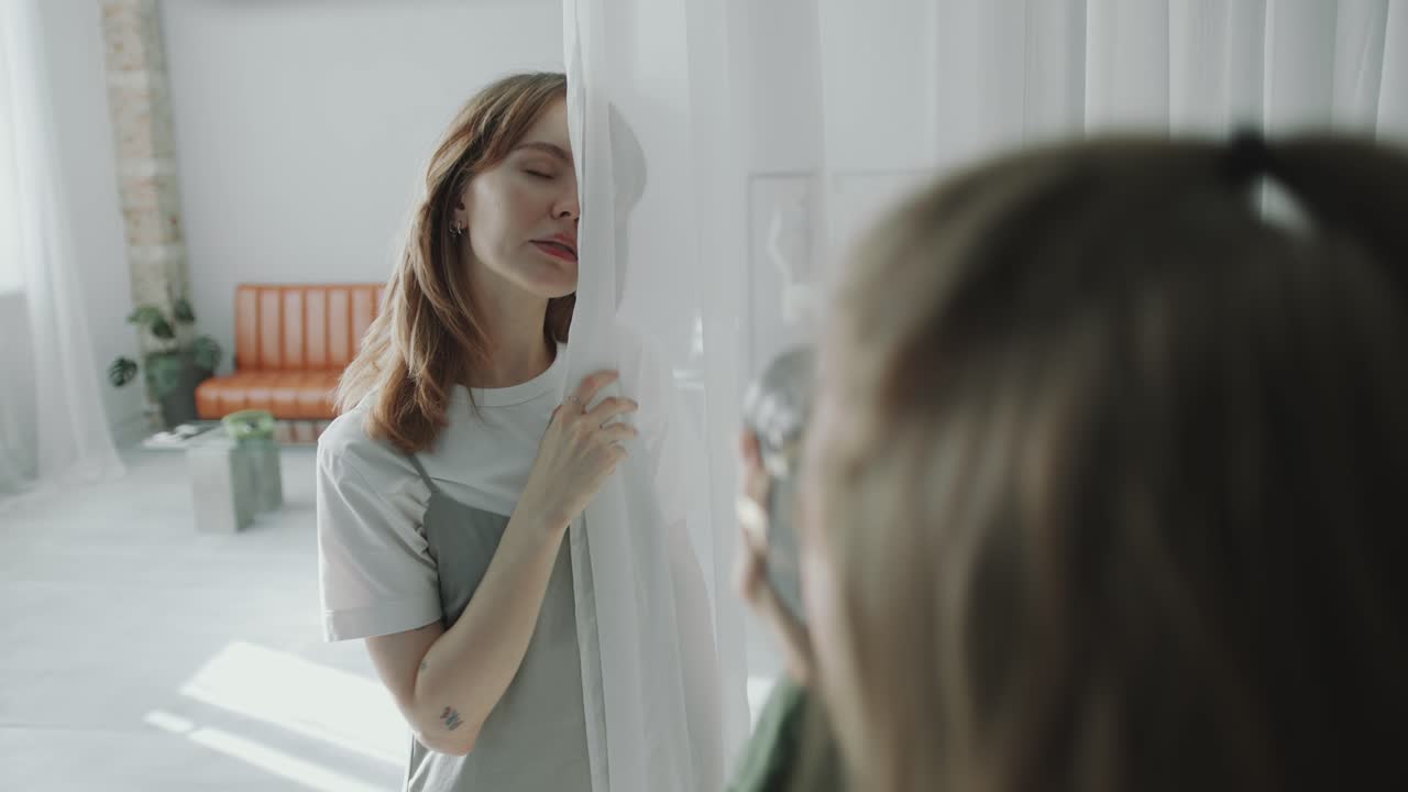 Photographer Taking Portraits of Beautiful Model Posing behind Sheer Curtain